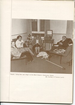 Four people sit in a lounge area, one lady knits whilst two ladies and a man listen to talking books.  Second man kneels at record player.