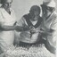 Man assisted by two nurses to cut cake celebrating his centenary birthday