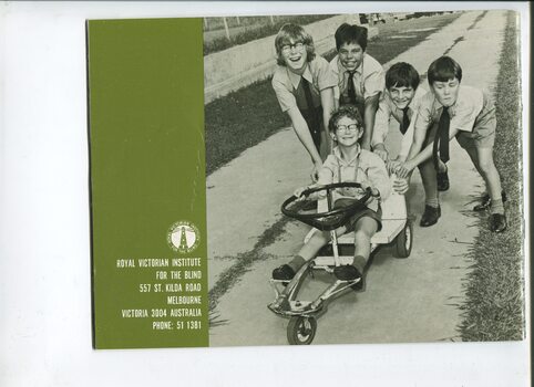 Four school boys push a fifth on a homemade race cart