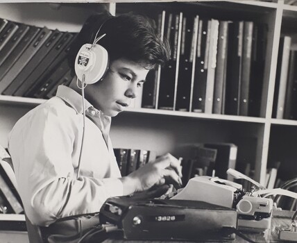 Young man types as he listens to a recording