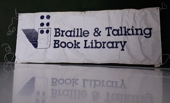 White banner with 'Braille & Talking Book Library' in dark blue and six dots rising from a folded paper