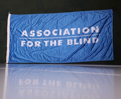 Blue flag with white writing 'Association for the Blind'