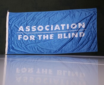 Blue flag with white writing 'Association for the Blind'