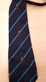 Navy blue tie with light blue diagonal stripe and guiding light symbol in yellow