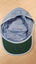 Blue cap with 'Association for the Blind' in navy writing and green on underside of front visor.