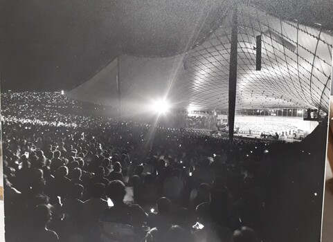 Lighted stage at night, taken from outer stage left over crowds