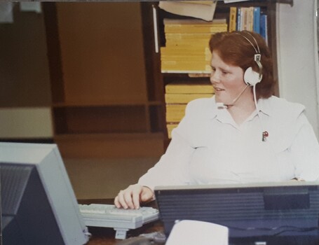 Woman wears headset whilst working on computer