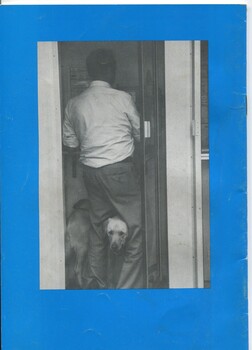 Image of man trying to walk through doorway, with a dog trying to push his way between the man's legs