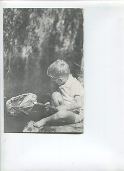 Child with fishing net beside a waterway