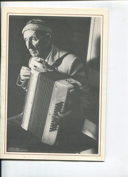 Blind musician sits as he plays his accordion