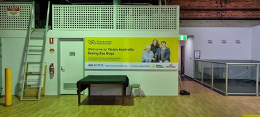 Yellow Vision Australia sign with blue writing on wall
