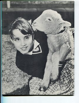 School girl holding a lamb who sniffs at her hair