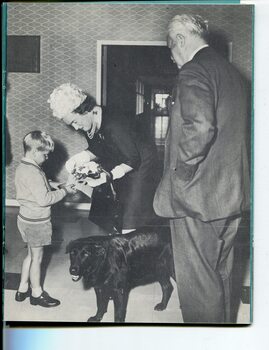 Timothy presenting flowers to Lady Delacombe whilst Sir Rohan Delacombe looks on