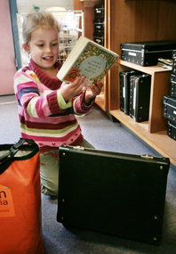 Kate holds book beside an open suitcase
