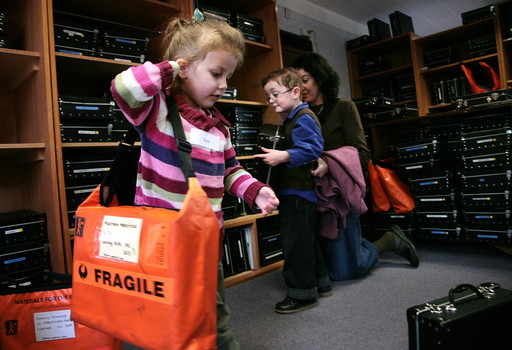 Kate holds bag on her shoulder in Feelix library with Dominic and Mum selecting a case