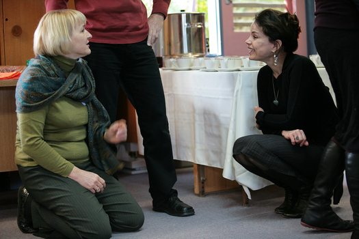 Sigrid Thornton kneeling as she speaks to another woman sitting on the floor of the Feelix library