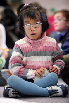 Anna investigating the train carriage in her hands as she sits cross legged on the mat