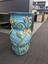 Light blue pot with vines, leaves, flowers, insects and words written in cursive and braille