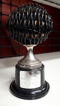 Blind cricket ball atop a metal holder with metal plaque on bakelite pedestal