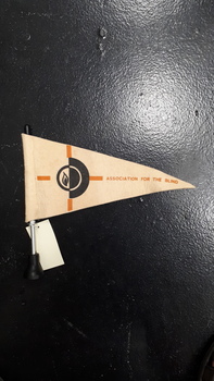 Cream felt flag with words 'Association for the Blind' in caramel, standing on black base