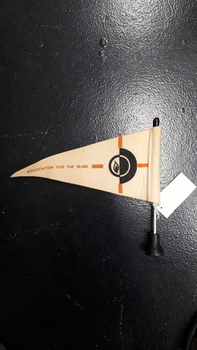 Cream felt flag with words 'Association for the Blind' in caramel, standing on black base