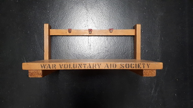 Wooden triangular stand with three red leather hooks across bar at top of stand