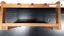 Wooden triangular stand with three red leather hooks across bar at top of stand