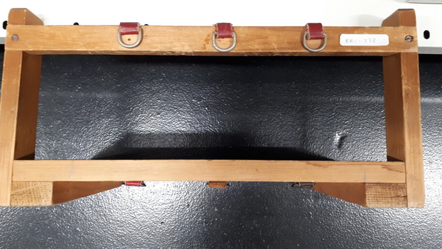 Wooden triangular stand with three red leather hooks across bar at top of stand
