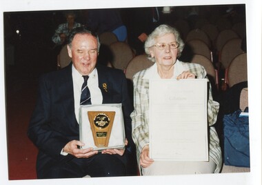 Neil Maxwell holds the award whilst Elizabeth holds the award citation