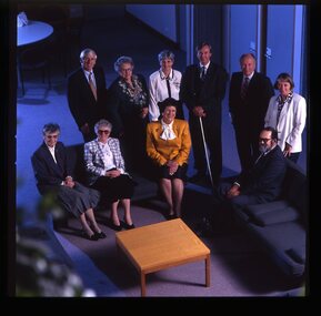 10 people seated around a small table looking up to the photographer on the floor above