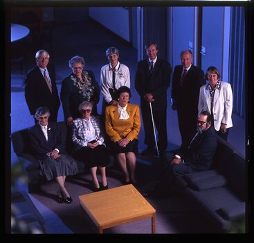 10 people seated around a small table looking up to the photographer on the floor above
