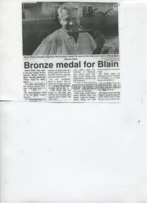 Article and photograph of man holding his medal