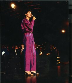 Keren Minshull wearing purple jumpsuit and singing to the crowd