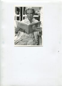 Older woman seated as she reads a book