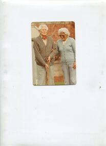 Male holds wooden stick whilst female smiles and looks on