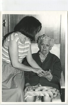 Younger woman fingerspells on to the palm of an older woman
