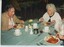 Three women sit at a table eating stewed meat and vegetables for lunch