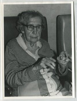 Older woman sits as she extends her arms and wriggles her fingers
