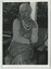 A woman toys with her beaded necklace as she sits and chats