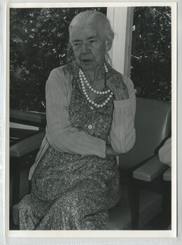 A woman toys with her beaded necklace as she sits and chats