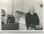 A man sits on the edge of his bed with his belongings around him