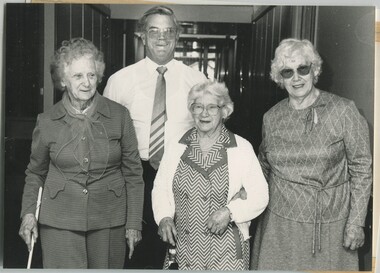 Don Dunstan walks behind three women along a corridor