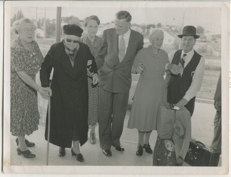 Two women walk with helpers holding their hands and arms