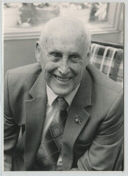 Man seated on chair wearing suit with AFB lapel pin