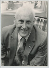 Man seated on chair wearing suit with AFB lapel pin