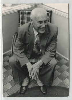 Man seated on chair wearing suit with AFB lapel pin