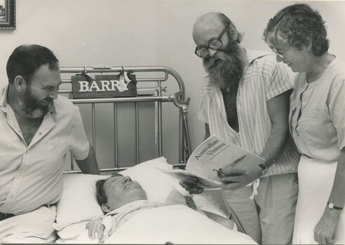 Barry Farnsworth smiling as he listens to James Egan, a woman and another man who sits on the bed