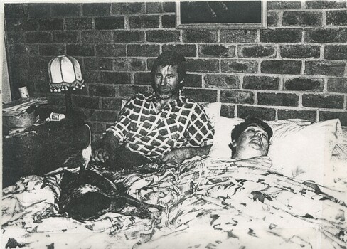 Barry Farnsworth with male friend and an Australian cattle dog sitting on the bed