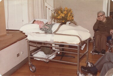 Barry Farnsworth in a trolley bed near the stage