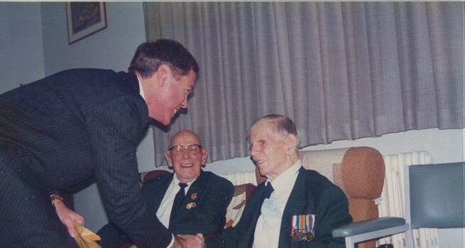 Jim Kibble shaking hands with Tony Carr, whilst Ted Thompson looks on